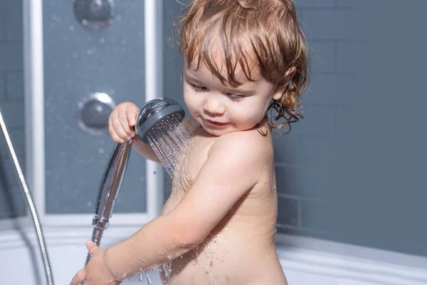 목욕하는 작은 아기, 웃는 소년, 건강 관리, 그리고 아이들 위생의 얼굴을 감쌌습니다. 샤워기 밑에서 목욕하는 어린이. — 스톡 사진