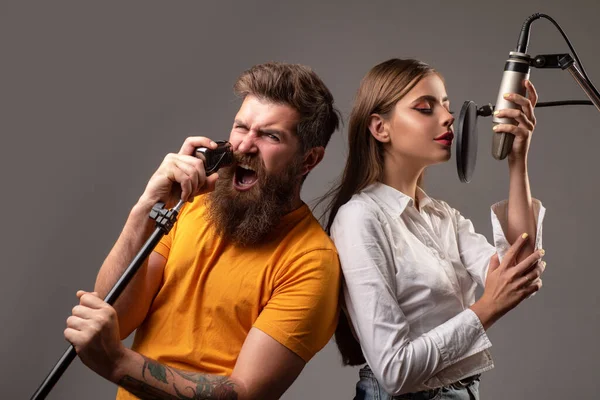 Jovens amigos com rostos animados gostam de música. Casal de cantores a cantar rock. Produção de som canção de gravação em um estúdio de música. Karaoke animado. — Fotografia de Stock