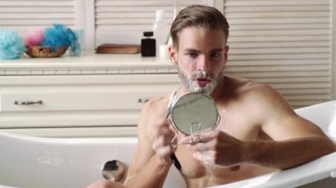 Bath or shower. Mens body care. Shaving beard. Handsome man in bathroom. Guy washes in shower. Morning routine.