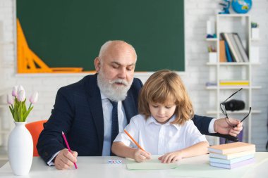 Öğrenci çocuk dersi. Lise son sınıf öğretmeni. Eğitim konsepti. Yaşlı büyükbaba ve okul çocuğu sınıfta..