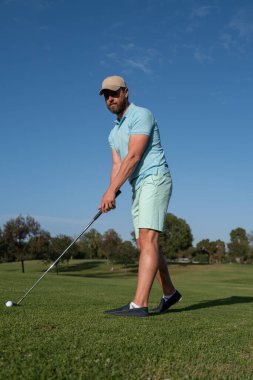 Golfçü adam güzel, güneşli yeşil golf sahasında golf oynuyor..