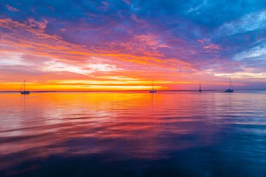 Gün batımında gökyüzü ve bulutların arasında güneş olan sakin bir deniz. Okyanus ve gökyüzü arkaplanı, deniz manzarası.
