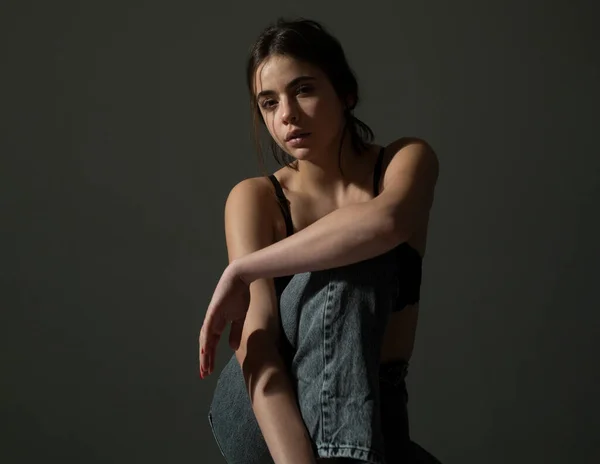 Ritratto di ragazza alla moda in reggiseno nero e jeans di jeans seduti e guardando la fotocamera. — Foto Stock