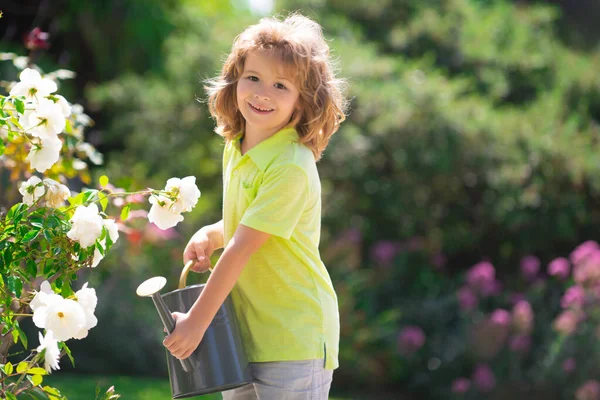 Милий маленький хлопчик дитина поливає квіти з балончиком. Дитячий садівництво . — стокове фото