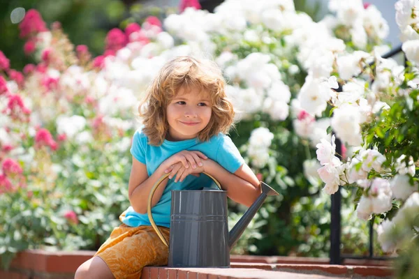 Little farmer with watering can in garden planting flowers. — Stock Photo, Image