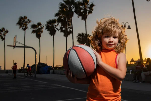 Çocuk basketbolcunun portresi. Çocuk basketbol topunu gün batımında sahanın dışında tutuyor.. — Stok fotoğraf