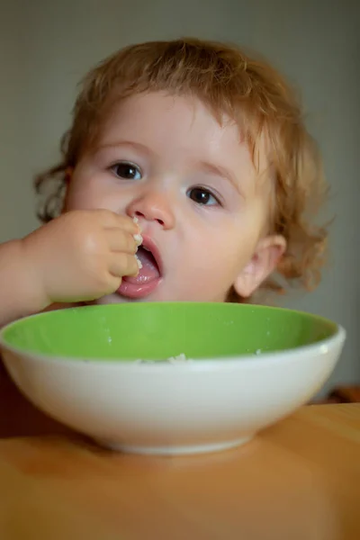 Ritratto di piccolo bambino divertente che mangia dal primo piano del piatto. — Foto Stock