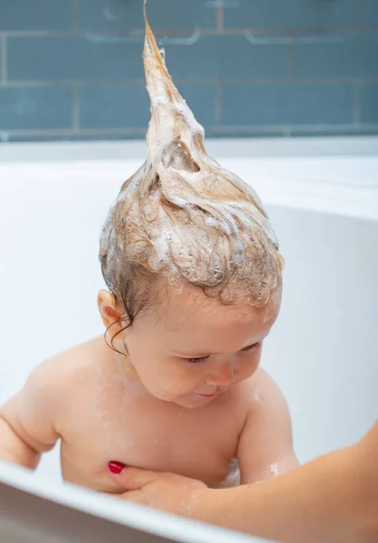 Usmívat se krásnému dítěti ve sprše. Koupající se dítě. Šťastné dítě s pěnou na hlavě. Dítě v koupelně hrát s pěnou. — Stock fotografie