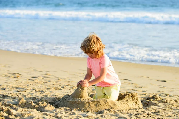 Çocuk yaz tatilinde plajda oynuyor. Çocuklar denizde kumdan kale yapıyorlar.. — Stok fotoğraf