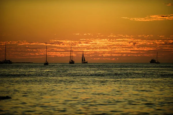 Barco en el mar al atardecer. Veleros con velas. Yate oceánico navegando en aguas oceánicas. — Foto de Stock