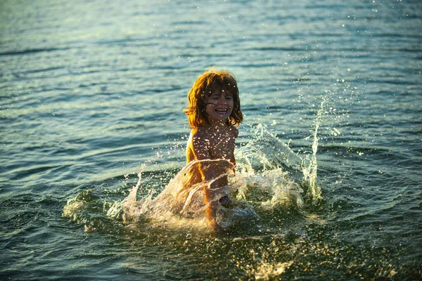Ragazzo che gioca in spiaggia durante le vacanze estive. Bambino in natura con bellissimo tramonto sul mare. Bambini felici in vacanza al mare in acqua. — Foto Stock