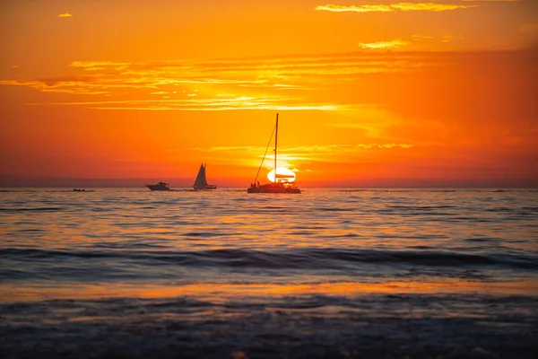 Naplemente a tengernél. Jacht vitorlázás a nyílt tengeren naplementekor. Naplemente a tengerben, gyönyörű felhőkkel. Napkelte, óceáni tengerpart. — Stock Fotó