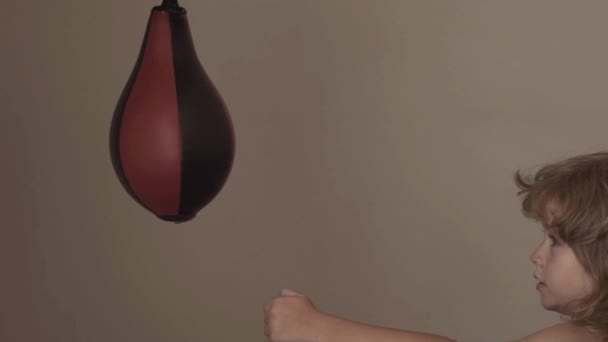 Malý mužský chlapec silně zasáhne boxerský pytel. — Stock video