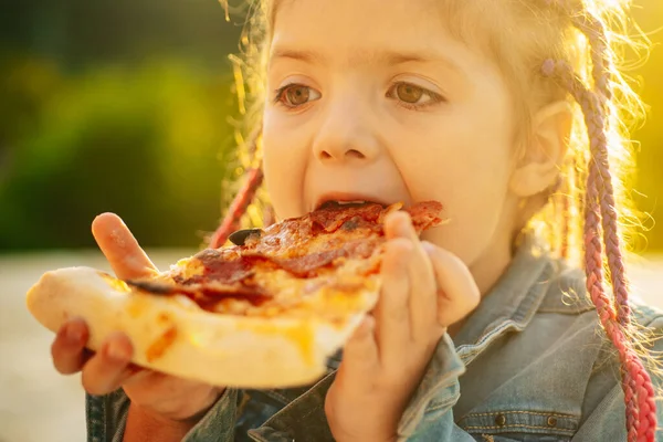 Çocukların en sevdiği yemek. Lezzetli pizza. Çocuk pizza yiyor. Fastfood. İtalyan abur cuburu. Küçük kız dışarıda öğle yemeği.. — Stok fotoğraf