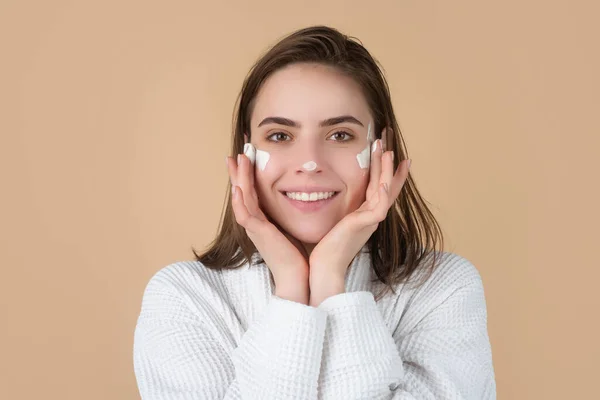 Vacker tjej modell med naturlig makeup tillämpa fuktighetskräm på hennes vackra ansikte. — Stockfoto