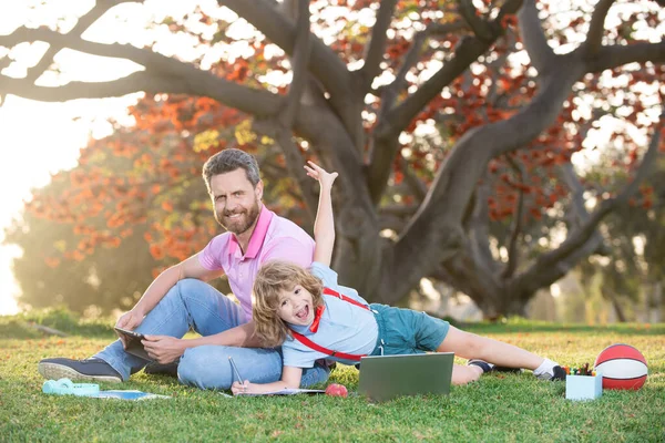 Pupil with teacher learning outdoor by studying online and working on tablet laptop in park.