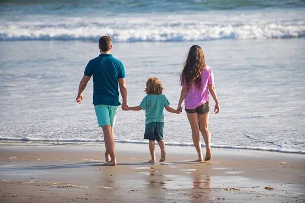 Achteraanzicht van gelukkige jonge familie wandelen op het strand. Kind met ouders die elkaars hand vasthouden. Een volwaardig gedicht. Familie reizen, vakantie concept. — Stockfoto