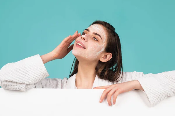 Mooie jonge vrouw met schone frisse huid aanbrengen gezichtscrème, gezichtsmasker crème, geïsoleerd. Banner met kopieerruimte. — Stockfoto