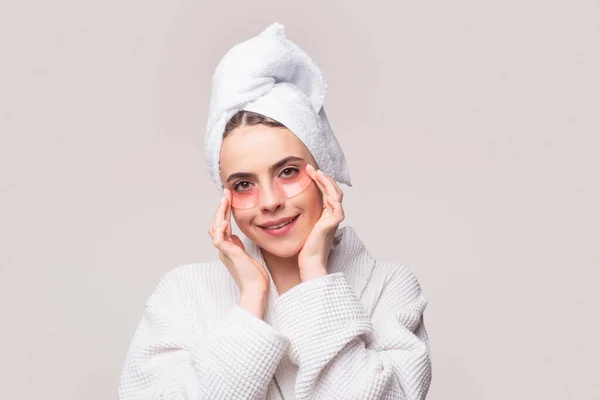 Mujer aplicando parches en los ojos. Muchacha de retratos con toalla en la cabeza. Retrato de mujer de belleza con parches en los ojos que muestran un efecto de la piel perfecta. Morena chica spa. —  Fotos de Stock