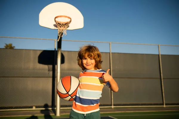 Glad liten pojke unge spelar basket på lekplatsen. — Stockfoto