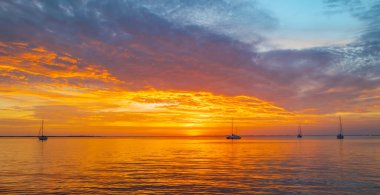 Gün batımında gökyüzü ve bulutların arasında güneş olan sakin bir deniz. Okyanus ve gökyüzü arkaplanı, deniz manzarası.