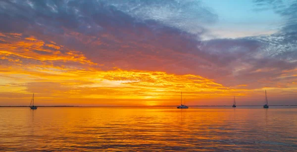 Gün batımında gökyüzü ve bulutların arasında güneş olan sakin bir deniz. Okyanus ve gökyüzü arkaplanı, deniz manzarası.