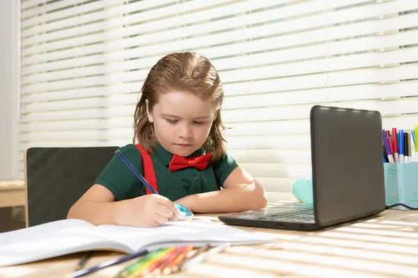 Un écolier intelligent fait ses devoirs en classe. Écrit du texte à partir d'un ordinateur portable portable. — Photo