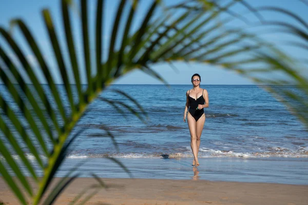 若い幸せな女性がビーチで裸足で走っている。夏のビーチと海. — ストック写真
