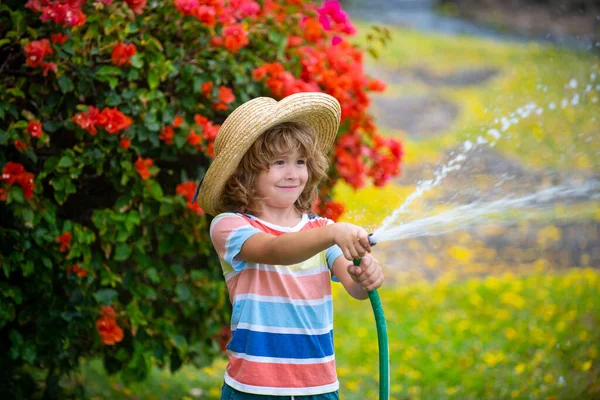 빨대를 쓴 귀여운 아이가 물뿌리는 호스로 웃고 있어요 — 스톡 사진
