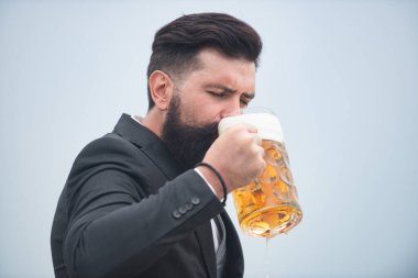 Sakallı ve bıyıklı hippi iş gününden sonra bira içer. Almanya Bavyera. Bira zamanı. Yakışıklı barmen elinde yarım litre bira tutuyor..