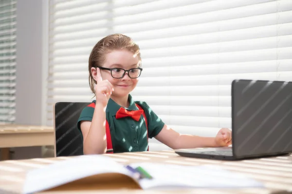 Smart school boy at home writing homework. Little student with notebook computer ready to study. School remote, online learning. Kid at home class learning.