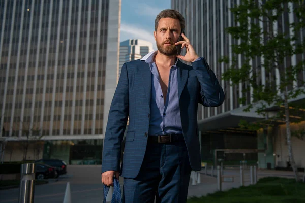 Hombre de negocios caucásico de traje sale de la oficina hablando por teléfono. concepto de jornada laboral final. Moda sexy hombre de negocios. —  Fotos de Stock