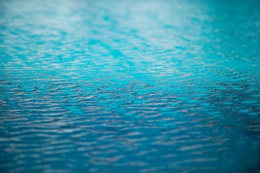 Mavi havuz suyu arka planı. Bulanık şeffaf, durgun su yüzeyi dokusu. Güneş ışığı altında su dalgaları kopyalama alanı ile.