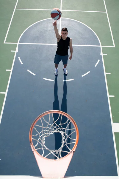 Akční záběr mladého muže hrajícího basketbal venku. Ručně točící se koš. Vyrovnávací basketbal na prstu. — Stock fotografie