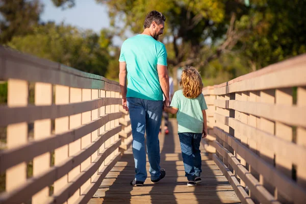 Vader met zoon wandelen op bosrijke brug buiten. — Stockfoto