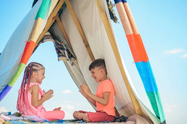A gyerekek jól érzik magukat a szabadban. Testvérek együtt játszanak. Boldog gyerekek játszanak a sátorban. Kempinggyerekek. — Stock Fotó