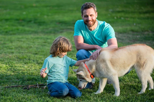 Pai e filho com cão de estimação relaxante na natureza no parque. — Fotografia de Stock