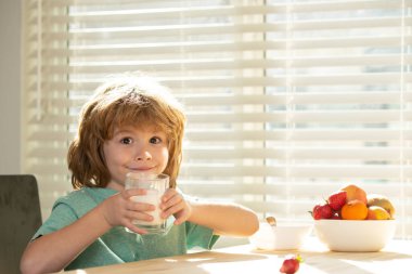 Çocuklar yemek yiyor. Sevimli küçük çocuk, camdan vitaminli kalsiyum içeren lezzetli organik süt içiyor. Küçük çocuk lezzetli besleyici laktozsuz yoğurdun tadını çıkarıyor. Çocuk beslenmesi.
