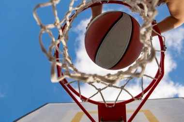 Sepet topu tutan sevimli küçük çocuk sayı yapmaya çalışıyor. Tepeden tırnağa uçan topun görüntüsü, çocuk basketbol oynuyor. Çocuklar için spor.