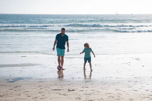 父と息子は夏休みにビーチでサッカーやサッカーをします。男性世代の概念. — ストック写真
