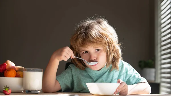 Portret van een schattig kind dat soep eet of ontbijt bij de tafel thuis met lepel. Kinderen gezond voedsel. — Stockfoto