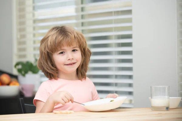 Портрет милого ребенка, поедающего суп или завтрак, обедающего дома за столом с ложкой. Здоровое питание. — стоковое фото