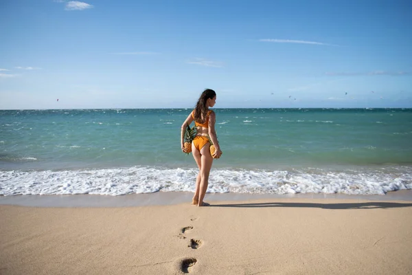 Femme mince ludique en bikini sexy se tient en arrière marche loin Hawaï ou Maldives plage de mer tenant ananas frais. Plage d'été chaude, maillots de bain pour femmes. — Photo