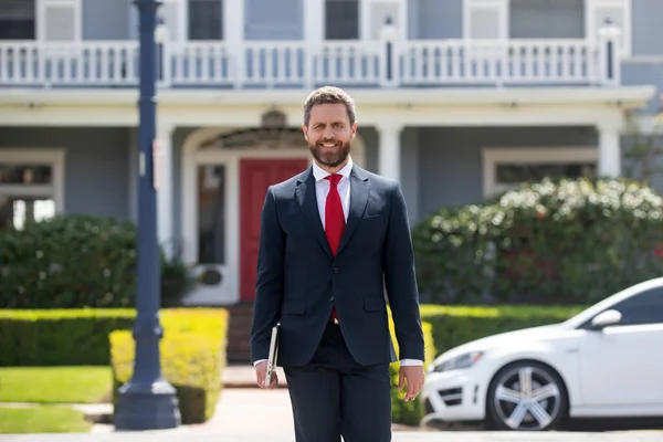 Geschäftsmann steht vor einem modernen Haus. Immobilienkonzept. Makler bereit, Haus zu verkaufen. — Stockfoto