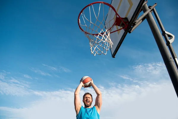 Maduro homem segurando basquete contra claro azul céu. — Fotografia de Stock