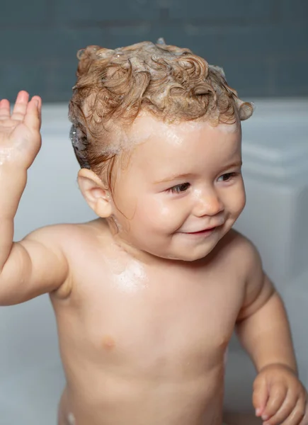 Dziecięca kąpiel. Zabawne szczęśliwe dziecko kąpie się w wannie z wodą i pianką. Higiena dzieci. — Zdjęcie stockowe