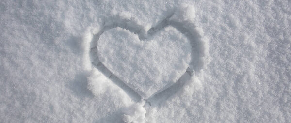 Heart on snow. Wintertime background. White background. Snow texture. Ice snowy background.