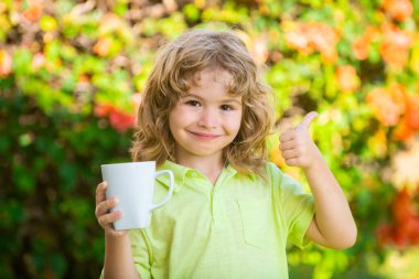 Genç çocuk güneşli bir yaz gününde bardaktan meyve suyu içiyor..