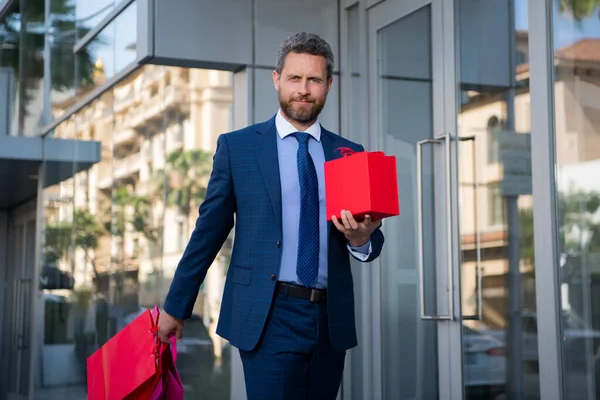 Un bel regalo. Uomo con scatola regalo e sorridente mentre in piedi contro la città. — Foto Stock