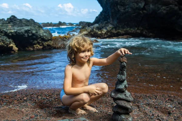 Deniz sahilinde zen taşları olan çocuk, meditasyon, spa ve uyum. Sakin denge kavramı.